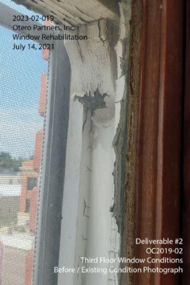 Third floor window frame with cracked paint and rotting wood.